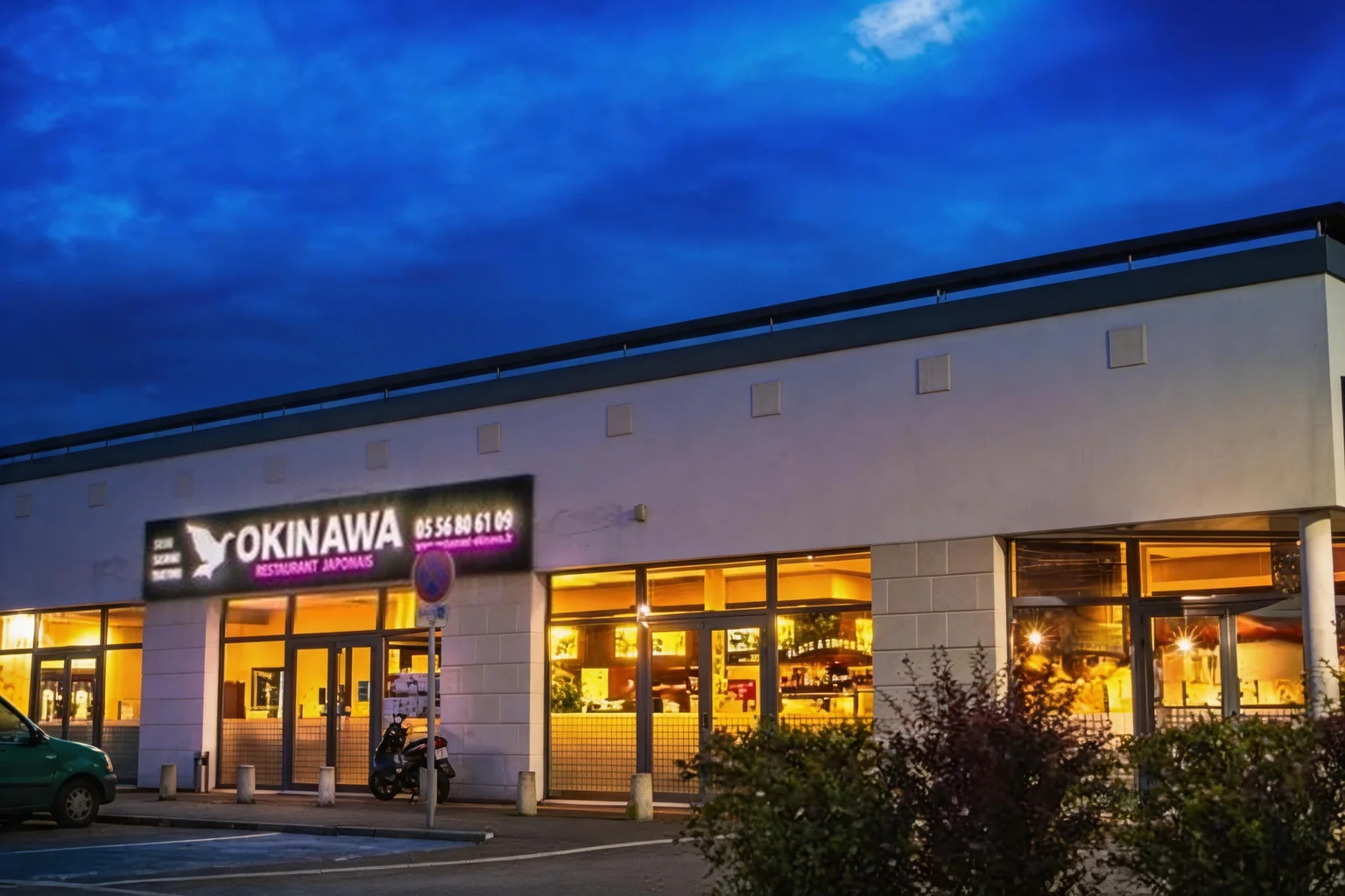 Façade du restaurant Okinawa le soir, enseigne lumineuse et vitrines éclairées.