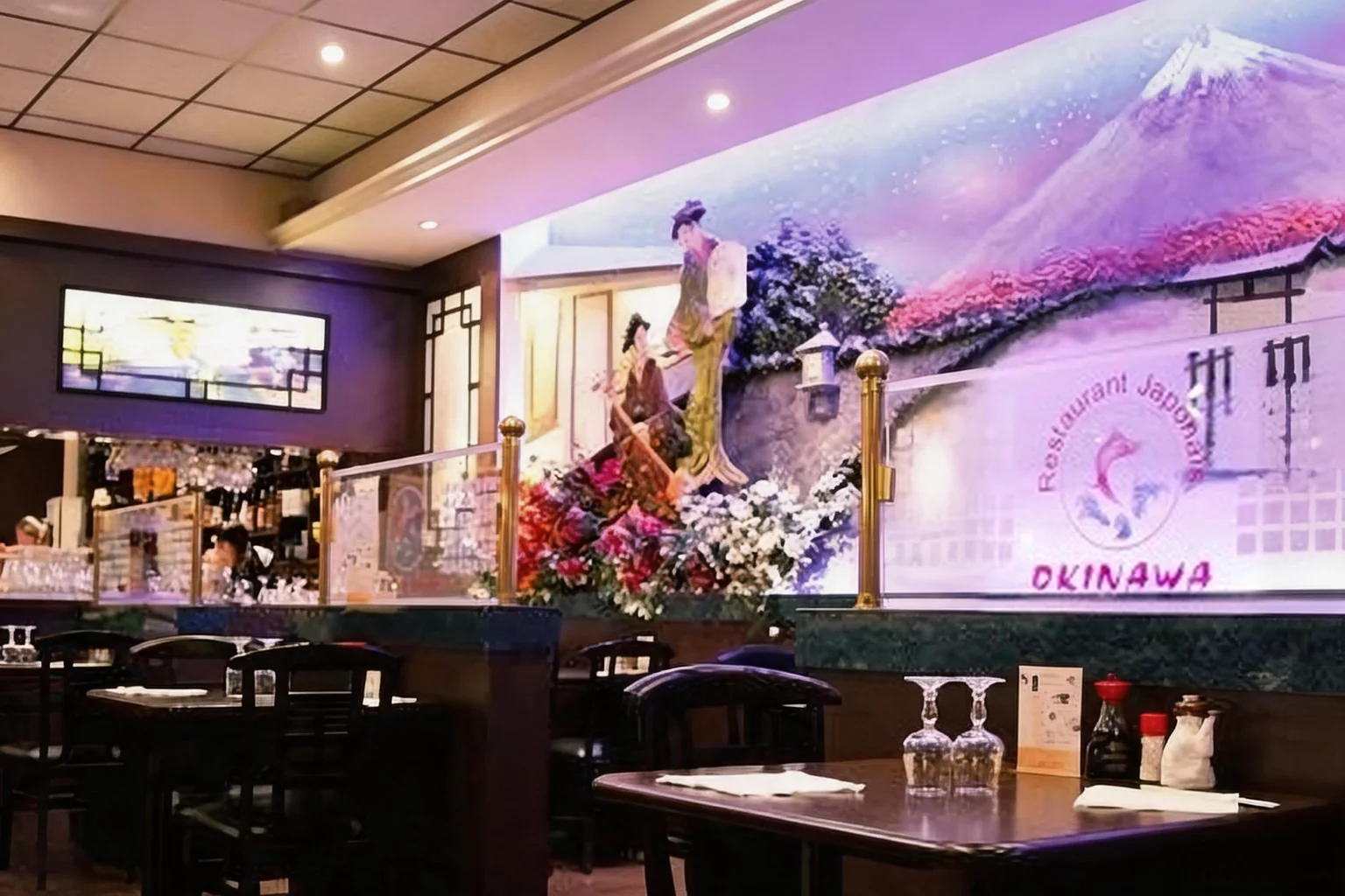 Salle du restaurant : fresque du mont Fuji, fleurs, tables et verres.